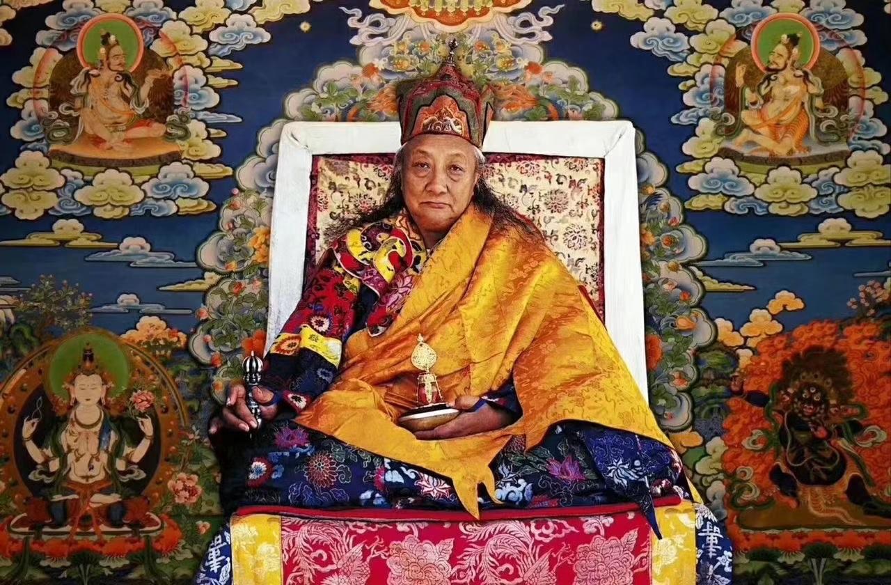 Dilgo Khyentse Rinpoche seated in yellow and red robes before a backdrop of Buddhist figures.